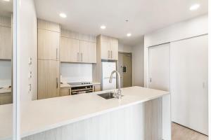 a kitchen with white cabinets and a sink at Vibrant Minimalism - City Views in Auckland