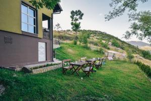 eine Gruppe von Tischen und Stühlen im Gras neben einem Gebäude in der Unterkunft Relaxing holiday house in Sarajevo