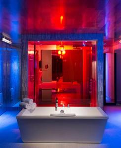 La salle de bains est pourvue d'un lavabo blanc et de lumières rouges. dans l'établissement Hôtel Le Rivage, à Rosemère