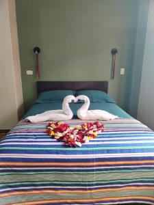two swans are laying on a bed with flowers at Inca´s Suite in Los Baños del Inca