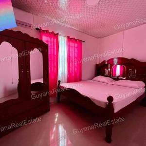 Schlafzimmer mit einem Bett mit rosafarbener Beleuchtung in der Unterkunft S&S Guyana Real Estate Apartment in Georgetown