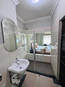 a bathroom with a sink and a mirror and a bed at The Pillows Suite in Pretoria