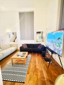 un soggiorno con divano e TV a grande schermo di Double height ceiling spacious city apartment a Sheffield