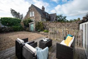 a patio with two wicker chairs and a house at Peewit Cottage in Belford