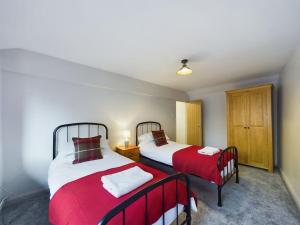 a bedroom with two beds with red and white sheets at Rosina Barn in Boddicott