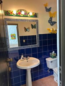 Baño de azulejos azules con lavabo y espejo en Quinta Las Victorias en El Valle de Antón