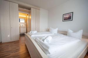 two beds in a room with white walls and wooden floors at Frische-Brise-11-06 in Cuxhaven