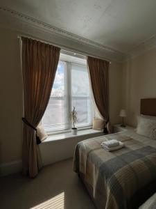 a bedroom with a bed and a large window at Acorn House Callander in Callander
