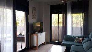 - un salon avec un canapé, une télévision et des fenêtres dans l'établissement Neo Mediterráneo, à Barrio-Mar