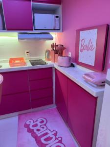 une cuisine avec des placards roses et un panneau barbier sur le comptoir dans l'établissement Barbie House POA, à Porto Alegre