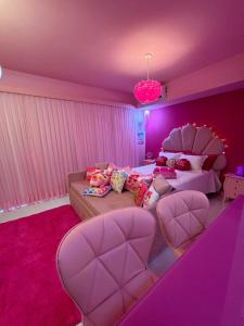 - une chambre rose avec un lit et un canapé dans l'établissement Barbie House POA, à Porto Alegre