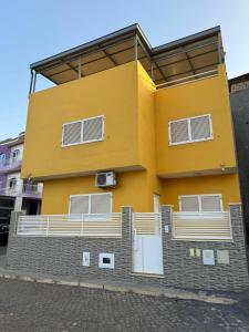 a yellow building with a balcony on the side of it at BemVinda Sweet Home - Cama Mesa e Fogão in Praia