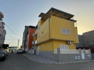 ein gelbes Gebäude an der Straßenseite in der Unterkunft BemVinda Sweet Home - Cama Mesa e Fogão in Praia