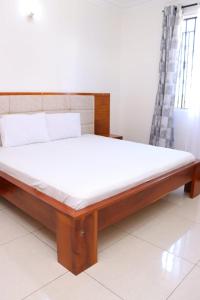 een bed met een houten frame en witte lakens bij Tollo 1br Utange Bamburi in Mombasa