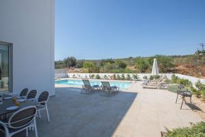 eine Terrasse mit Tischen und Stühlen neben einem Pool in der Unterkunft Ferienhaus für 10 Personen in Protaras, Südküste von Zypern - b59033 in Protaras
