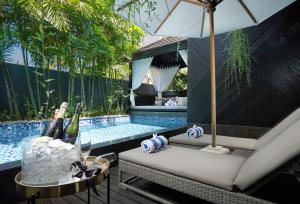 a swimming pool with a table with bottles of champagne at Villa Balimu Seminyak in Seminyak
