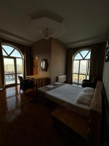 a bedroom with a bed and a desk and windows at Red Roof Seaview Hotel in Baku