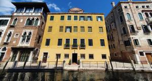 un edificio amarillo sentado junto a un río en Ca' Messner 5 Leoni en Venecia