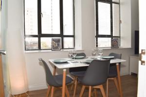 una sala da pranzo con tavolo, sedie e finestre di Vibrant Serviced Apartment In Central Birmingham a Birmingham