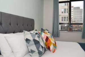 una camera con letto, finestra e cuscini di Vibrant Serviced Apartment In Central Birmingham a Birmingham
