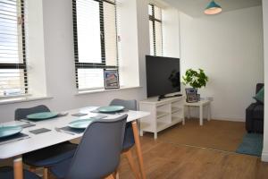 una sala da pranzo con tavolo, sedie e TV di Vibrant Serviced Apartment In Central Birmingham a Birmingham