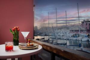 a table with a vase of flowers and a window with boats at NH Collection Genova Marina in Genova