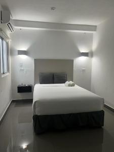 um quarto com uma grande cama branca num quarto em Hotel HSR em Cidade do Panamá