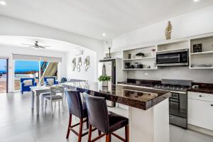 eine Küche mit weißen Wänden und einer Theke mit Stühlen in der Unterkunft Casa Capri 39 - Playa Arcangel in Rosarito