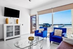 a living room with two blue chairs and a tv at Casa Capri 39 - Playa Arcangel in Rosarito