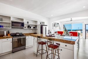 a kitchen with white cabinets and a island with bar stools at Casa Borgoña 40 - Playa Arcangel in Rosarito