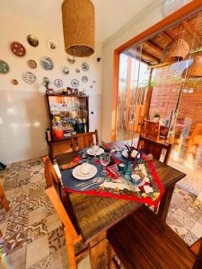 comedor con mesa, sillas y platos en Pousada Vila dos Corais - Taipu de Fora, en Maraú