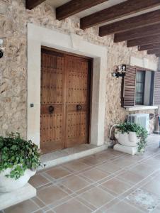a wooden door in a stone building with two pots at Son Pujol in Las Ollerías