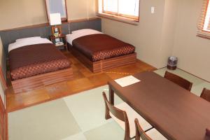a room with two beds and a table and chairs at Hotel Saika in Fujisawa