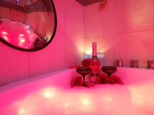 Una bañera rosa con una botella y dos copas de vino. en GDAŃSK by the Sea - PRESTIGE HOME SPA Apartments with a luxurious JACUZZI, SAUNA and an exclusive Massage Chair available in one of the apartments!, en Gdansk 221 fotos más