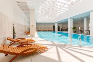 a large swimming pool with chairs and a swimming pool at Stellarlux Apartment, 35th floor in Skopje
