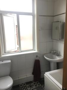 een badkamer met een toilet, een wastafel en 2 ramen bij Double room near City Centre in Manchester