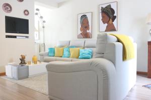 a living room with a white couch with colorful pillows at Espaço Jandira in Fajã de Baixo