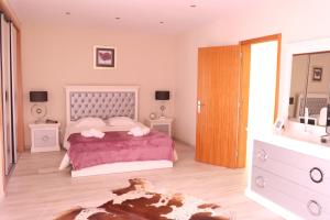 a bedroom with a bed with pink sheets and a mirror at Espaço Jandira in Fajã de Baixo