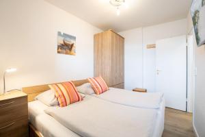 ein Schlafzimmer mit einem Bett mit orangefarbenen und weißen Kissen in der Unterkunft Berliner Hof - HOF/210 in Scharbeutz