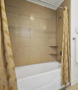 a bathroom with a tub and a shower curtain at Urban Oasis Your Perfect Getaway in the Heart of Downtown! in Houston