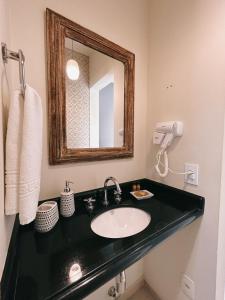 a bathroom with a sink and a mirror at Apart Avenida Monte Verde in Monte Verde