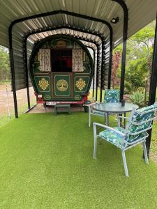 a table and chairs in front of a train at Gertrude Gypsy Wagon River Heads in River Heads