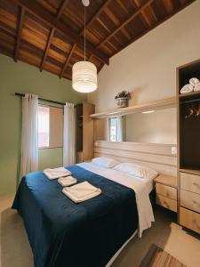 a bedroom with a large bed with towels on it at Apart Avenida Monte Verde in Monte Verde