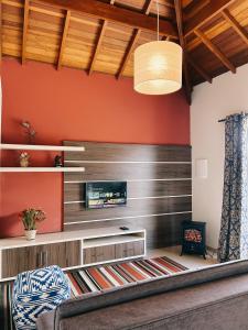 a living room with red walls and a flat screen tv at Apart Avenida Monte Verde in Monte Verde