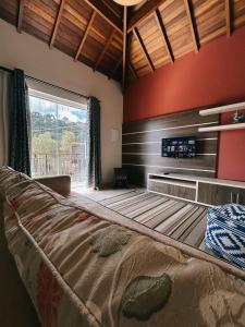 a bedroom with a bed and a large window at Apart Avenida Monte Verde in Monte Verde