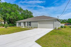 a white house with a garage in a yard at spacious 4-bedroom WITH KING BED in Palm Coast