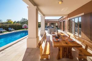 une table en bois sur une terrasse à côté d'une piscine dans l'établissement Ferienhaus mit Privatpool für 10 Personen ca 310 qm in Barban, Istrien Bucht von Raša, à Barban 14 autres photos