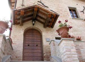 - un bâtiment en briques avec une porte en bois et des fleurs dans l'établissement Ferienhaus für 25 Personen und 2 Kinder in Citta di Castello, Trasimenischer See, à Città di Castello