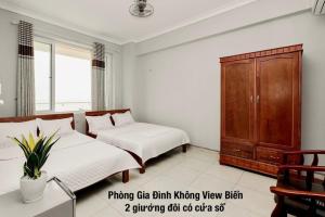 - une chambre avec un lit et une armoire en bois dans l'établissement Khách sạn Hà Nội 2 Mặt Biển Sầm Sơn, à Sầm Sơn