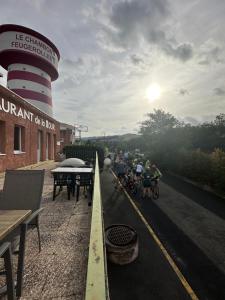 a group of people riding bikes down a road next to a lighthouse at HOTEL De La Tour Saint Etienne SUD in Saint Etienne